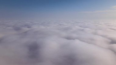 Dünya 'nın yüksek irtifasındaki uçak penceresinden hava manzarası beyaz kabarık kümülüs bulutlarıyla kaplı.