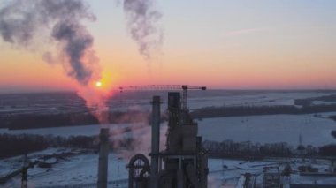 Gün batımında endüstriyel üretim alanında yüksek beton yapılı çimento fabrikası kulesinin havadan görüntüsü. Üretim ve küresel sanayi kavramı