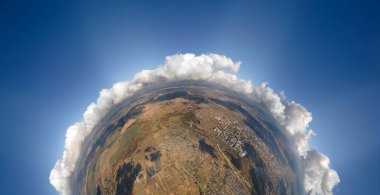 Küçük gezegenin yüksek irtifasından, yağmurdan önce oluşan kabarık kümülüs bulutlarıyla kaplı uzak bir şehrin havadan görüntüsü. Bulutlu manzaraya uçak bakışı