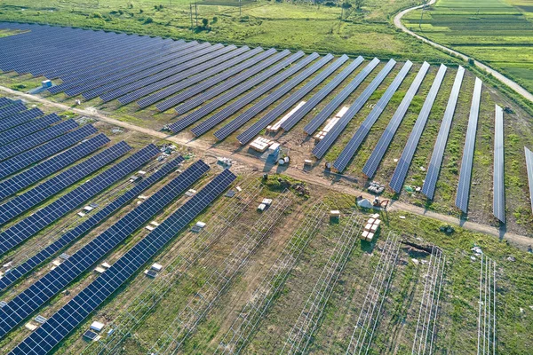 Vue aérienne de la grande centrale électrique en construction avec de nombreuses rangées de panneaux solaires sur châssis métallique pour produire de l'énergie électrique propre. Développement des sources d'électricité renouvelables — Photo