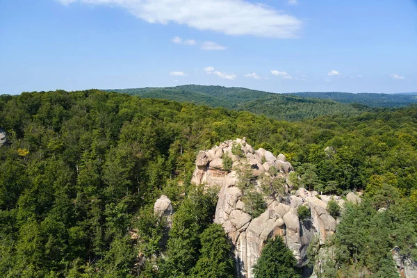 Aerial view of bright landscape with green forest trees and big rocky boulders between dense woods in summer. Beautiful scenery of wild woodland — Stock Photo, Image
