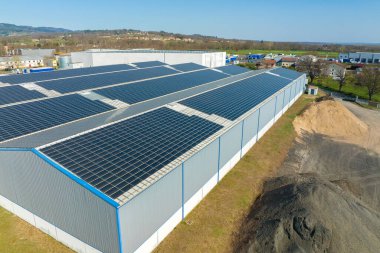 Sanayi binasının çatısına yeşil ekolojik elektrik üretmek için monte edilmiş mavi fotovoltaik panelli güneş enerjisi santralinin hava görüntüsü. Sürdürülebilir enerji konsepti üretimi