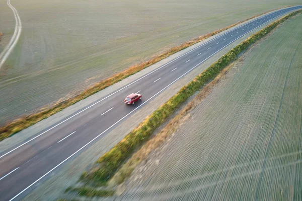 Aerial view of intercity road with blurred fast driving car at sunset. Top view from drone of highway traffic in evening — Stock Photo, Image