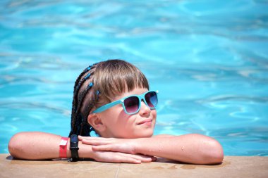 Mutlu kız çocuğu güneşli yaz gününde havuz kenarında dinleniyor.