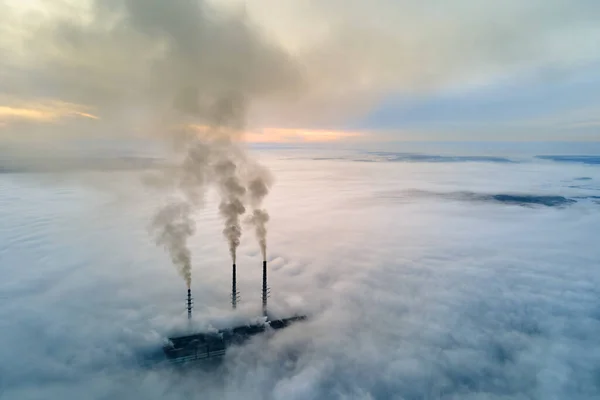 Вугільна електростанція має високі труби з чорним димом, що рухається вгору забруднюючи атмосферу. Виробництво електроенергії з концепцією викопного палива — стокове фото