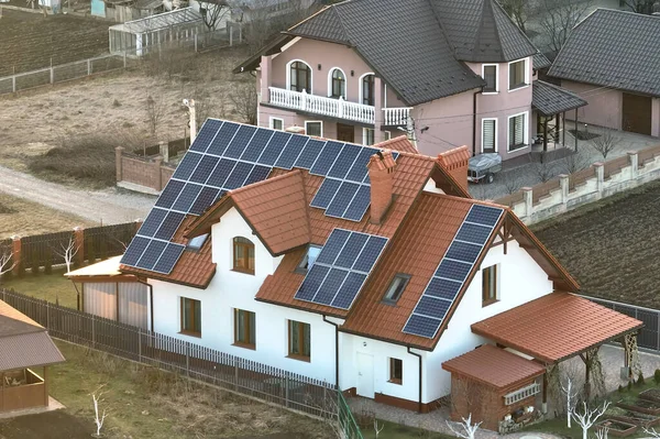 Жилой дом с крышей, покрытый солнечными фотоэлектрическими панелями для производства экологически чистой электроэнергии в пригородной сельской местности. Концепция автономного дома — стоковое фото