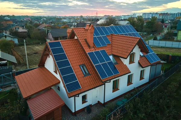 Κατοικία με στέγη που καλύπτεται με ηλιακούς φωτοβολταϊκούς συλλέκτες για την παραγωγή καθαρής οικολογικής ηλεκτρικής ενέργειας σε προαστιακή αγροτική περιοχή. Έννοια της αυτόνομης κατοικίας — Φωτογραφία Αρχείου
