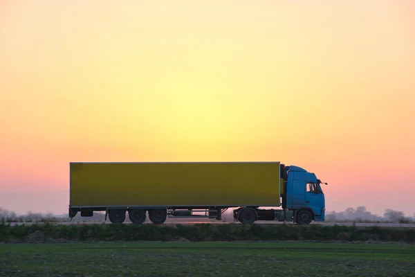 Semi-truck with cargo trailer driving on highway hauling goods in evening. Delivery transportation and logistics concept