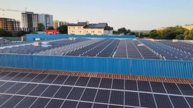 Sanayi binasının çatısına yeşil ekolojik elektrik üretmek için monte edilmiş mavi fotovoltaik panelli güneş enerjisi santralinin hava görüntüsü. Sürdürülebilir enerji konsepti üretimi