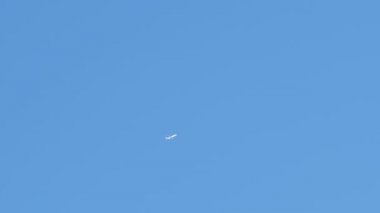 Mesafeli yolcu jet uçağı açık mavi gökyüzünde yüksek irtifada uçarken ardında beyaz duman izi bırakıyor. Hava taşımacılığı kavramı