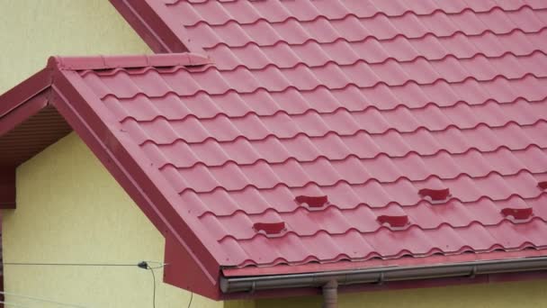 Osłona przeciwśnieżna zimą na dachu domu pokryta stalowymi gontami. Pokrycie okładziną budynku — Wideo stockowe