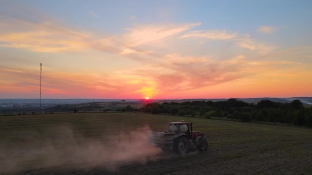 Traktorbesprutning av gödselmedel med bekämpningsmedel mot insekter på jordbruksmark vid solnedgången — Stockvideo