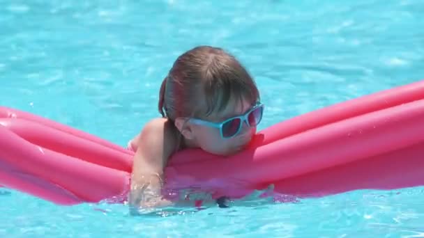 Young child girl falling in water from inflatable air mattress in swimming pool while swinnimg during tropical vacations. Safety of aquatic activities concept — Stock Video