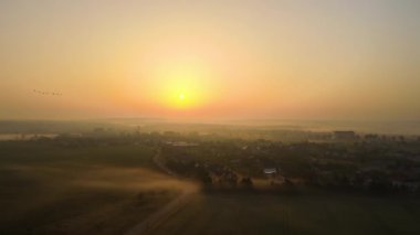 Kırsal kesimdeki yerleşim evleri üzerinde hava manzaralı sisli gün doğumu.