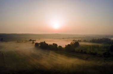 Parlak renkli günbatımı gökyüzü, batan güneş ve canlı bulutlar, karanlık manzaranın üzerinde..