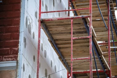 İnşaat iskelesi ile yenilenen bina cephesi. Enerji tasarruflu ev için köpük çarşaflı duvar yalıtımı.