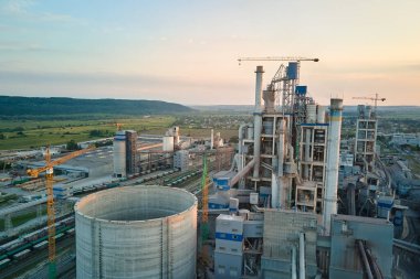 Yüksek fabrika yapısı olan çimento fabrikası ve endüstriyel üretim bölgesinde kule vinçleri var. Üretim ve küresel sanayi kavramı.