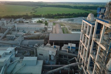 Yüksek fabrika yapısı olan çimento fabrikası ve endüstriyel üretim bölgesinde kule vinçleri var. Üretim, küresel sanayi ve hava kirliliği kavramı.