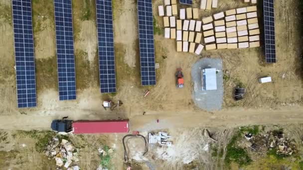 電気エネルギーを生産するための金属フレーム上の太陽電池パネルの組立部品を提供トラックと建設中の電気発電所の空中ビュー 再生可能エネルギーの開発 — ストック動画