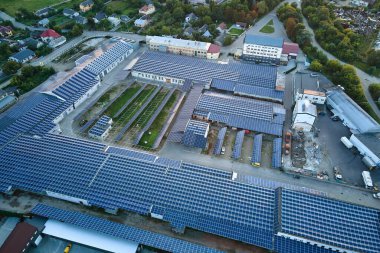 Sanayi binasının çatısına yeşil ekolojik elektrik üretmek için monte edilmiş mavi fotovoltaik panelli güneş enerjisi santralinin hava görüntüsü. Sürdürülebilir enerji konsepti üretimi.