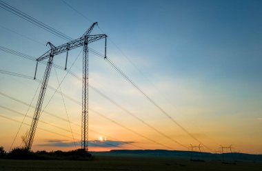 Gün batımında elektrik hatları olan yüksek voltaj kuleleri..