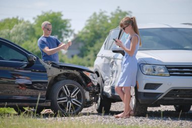 Stresli kadın ve erkek sürücüler trafik kazası üstüne trafik kazası sonrası cep telefonu kamerasıyla fotoğraf çekiyorlar. Yol güvenliği ve sigorta kavramı.