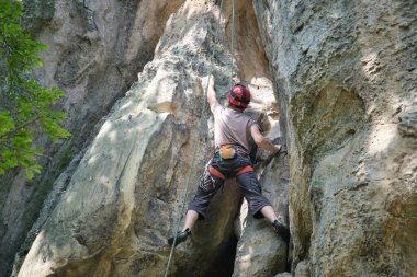 Güçlü erkek tırmanıcı kayalık dağın dik duvarına tırmanıyor. Sporcu zor yolu aştı. Ekstrem spor hobisi konsepti.