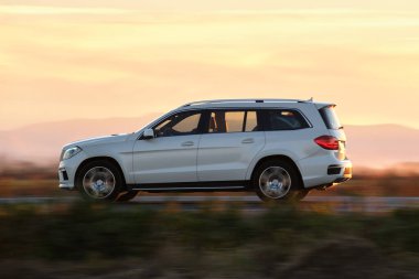 Gün batımında şehirlerarası yolda hızla giden bir SUV arabası. Akşamları otoyol trafiği.
