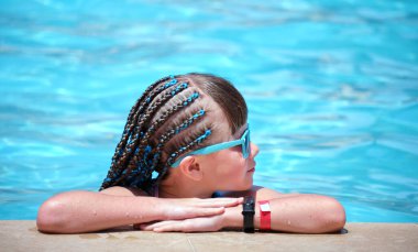Neşeli genç kız güneşli yaz gününde açık mavi suyla havuz kenarında dinleniyor. Tropik tatil kavramı.