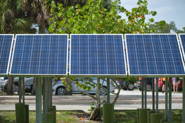 Solar panels installed on stand frame near parking lot for effective generation of clean electricity. Photovoltaic technology integrated in urban infrastructure for electric car charging.