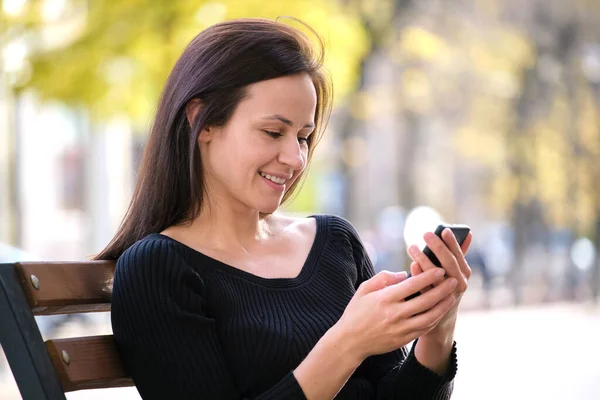 Молодая Женщина Сидя Скамейке Парке Просматривает Свой Мобильный Телефон Открытом — стоковое фото