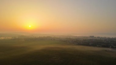 Aerial view foggy sunrise over residential houses in suburban rural area.