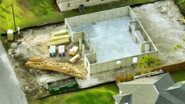 Tamamlanmamış, beton duvarlı, inşaat halindeki ahşap çatı kirişleri monte etmeye hazır özel evin havadan görüntüsü..