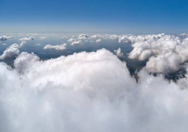 Dünya 'nın yüksek irtifasındaki uçak penceresinden hava manzarası beyaz kabarık kümülüs bulutlarıyla kaplı..
