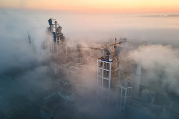 霧の夜に工業生産現場で高いコンクリート工場構造とタワークレーンとセメント工場の空中ビュー 生産とグローバル産業の概念 — ストック写真