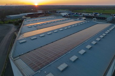 Mavi fotovoltaik güneş panelleri gün batımında temiz ekolojik elektrik üretmek için çatıya monte edildi. Yenilenebilir enerji konsepti üretimi.