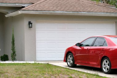 Car parked in front of wide garage double door on concrete driveway of new modern american house.