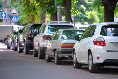 Sokak kenarında park halindeki arabalarla şehir trafiği.