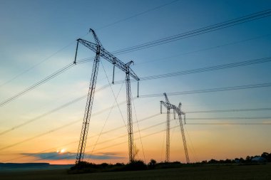 Güneş doğarken elektrik hatları olan yüksek voltajlı kulelerin koyu gölgesi..
