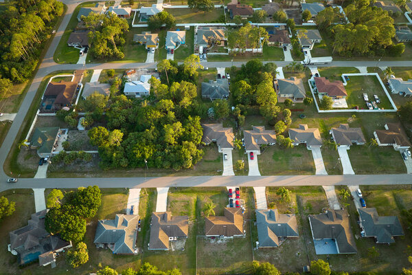 Aerial view of suburban landscape with private homes between green palm trees in Florida quiet residential area.