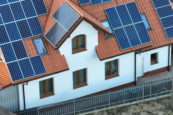 Residential house with rooftop covered with solar photovoltaic panels for producing of clean ecological electrical energy in suburban rural area. Concept of autonomous home.