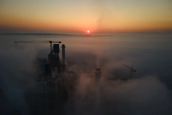 霧の朝に工業生産現場で高いコンクリート工場構造とタワークレーンとセメント工場の空中ビュー 製造業とグローバル産業の概念 — ストック写真