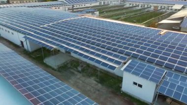 Sanayi binasının çatısına yeşil ekolojik elektrik üretmek için monte edilmiş mavi fotovoltaik panelli güneş enerjisi santralinin hava görüntüsü. Sürdürülebilir enerji konsepti üretimi.