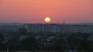 Güneş batarken akşam manzarası Uzak şehrin yüksek binalarının üzerinde gün batımında.