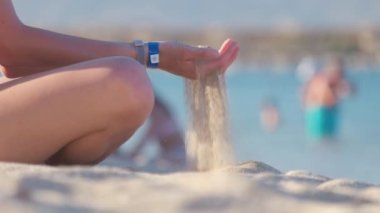 Kadın eli kapalı, deniz kenarına kum dökülüyor. Yaz plajı tatil konsepti.