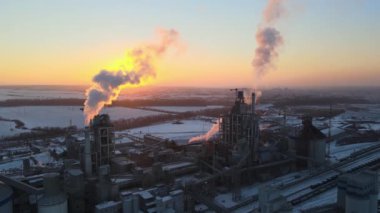 Gün batımında endüstriyel üretim alanında yüksek beton yapılı çimento fabrikası kulesinin havadan görüntüsü. Üretim ve küresel sanayi kavramı.