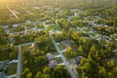 Aerial landscape view of suburban private houses between green palm trees in Florida quiet rural area at sunset.