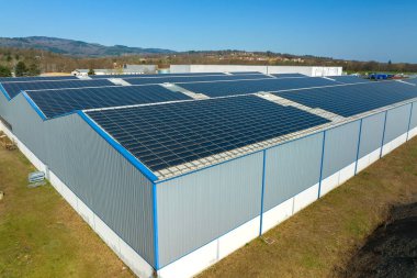 Sanayi binasının çatısına yeşil ekolojik elektrik üretmek için monte edilen mavi fotovoltaik güneş panellerinin hava görüntüsü. Sürdürülebilir enerji konsepti üretimi.