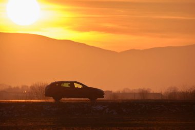 Gün batımında şehir içi yolda hızlı giden bir araba. Akşamları otoyol trafiği.