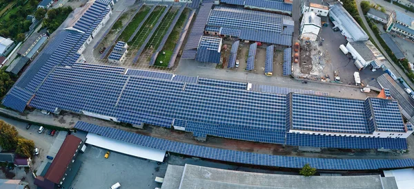 Sanayi binasının çatısına yeşil ekolojik elektrik üretmek için monte edilen mavi fotovoltaik güneş panellerinin hava görüntüsü. Sürdürülebilir enerji konsepti üretimi.